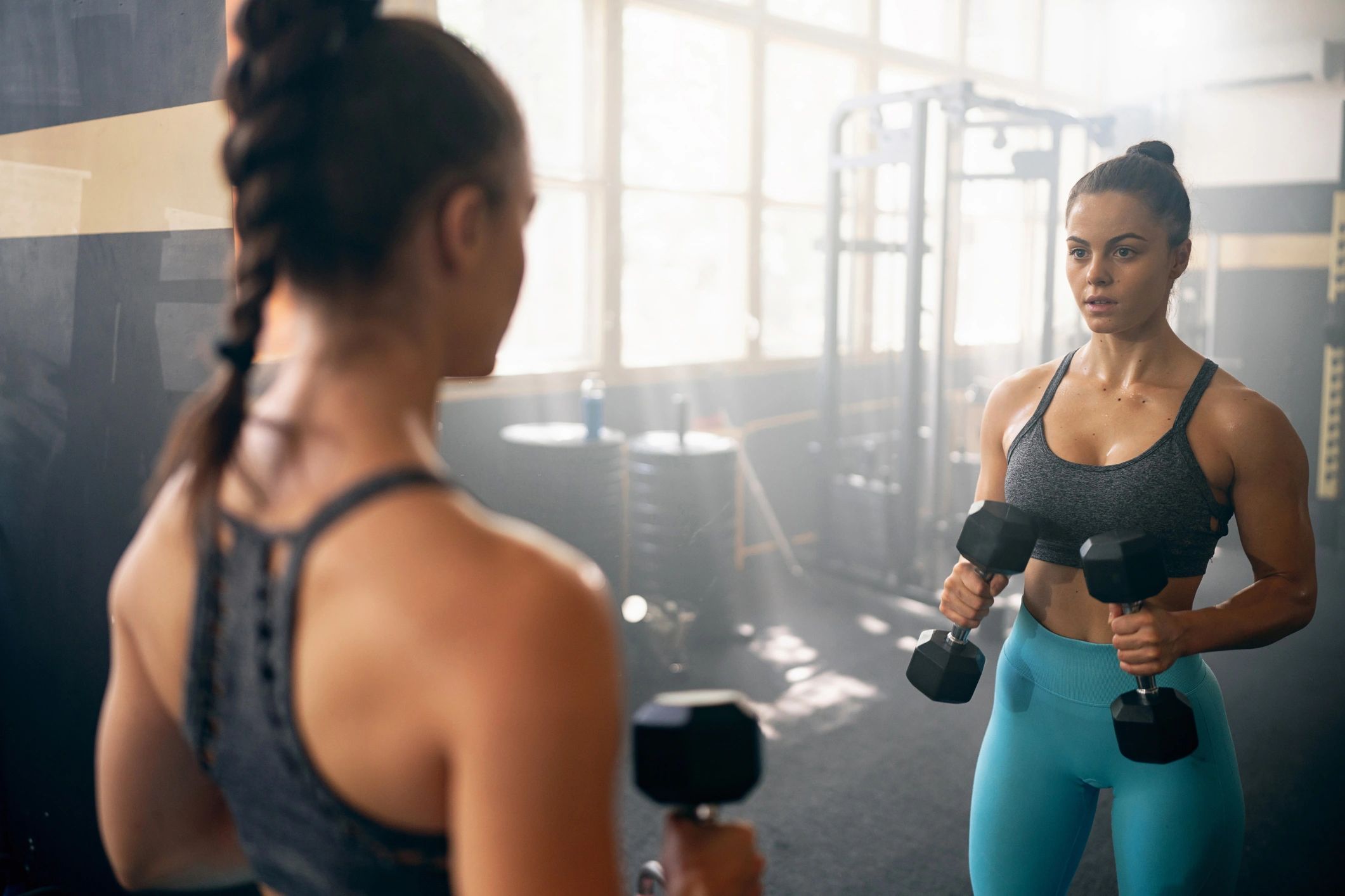 Woman lifting dumbbells while watching form in a mirror