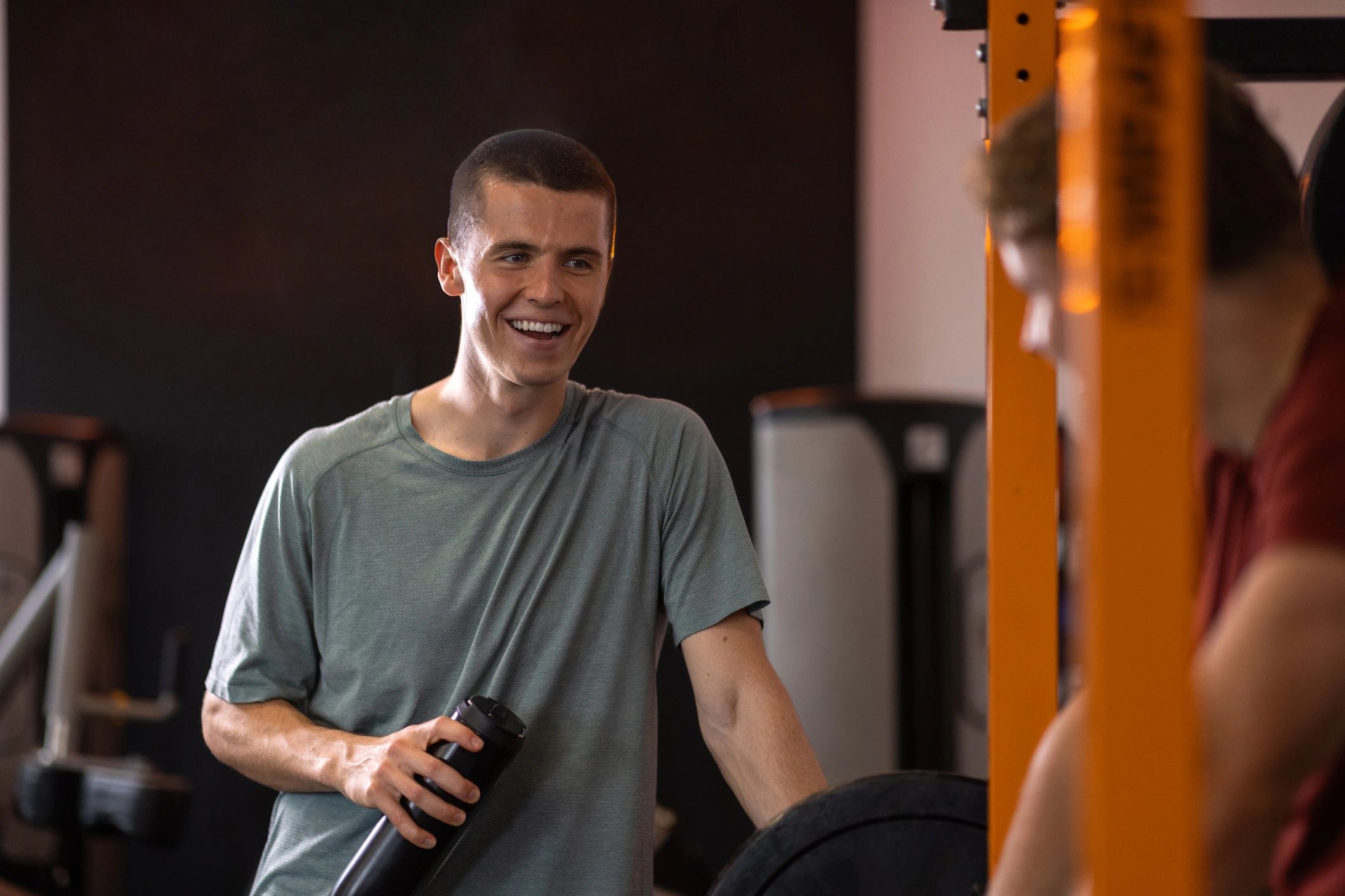 Personal trainer and client smiling near a squat rack